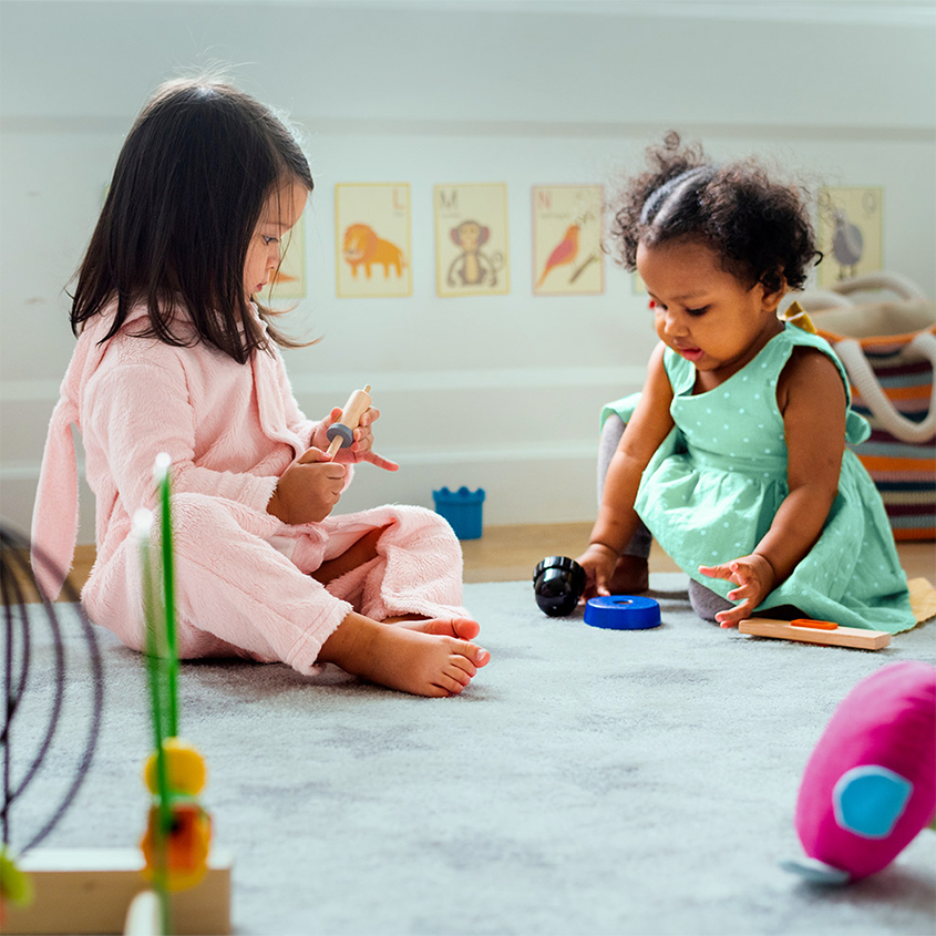 Two toddlers playing with toys on floor